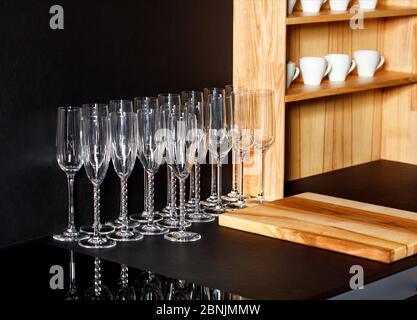 Verres à champagne sur un comptoir noir, tasses en porcelaine sur une étagère en bois vaisselle encore vie, fond sombre, espace de copie. Banque D'Images