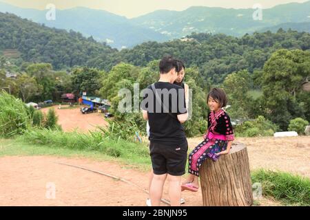 Touristes parlant à une jeune fille Hmong portant une robe traditionnelle au point de vue de la montagne de mon Cham, province de Chiang Mai, Thaïlande Banque D'Images