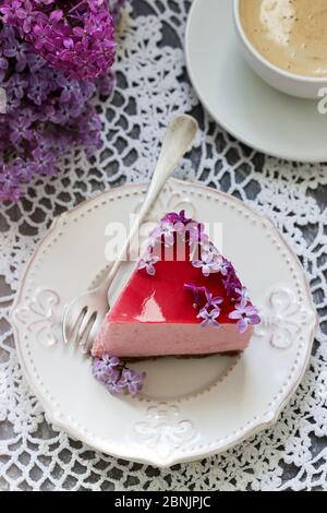 Un gâteau de mousse aux baies à base de chocolat et de jus de gelée, décoré de fleurs de lilas, servi avec du café. Banque D'Images