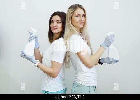 Deux femmes tiennent une bouteille vaporisée avec un antiseptique ou un détergent comme des pistolets. Concept de santé ou de nettoyage Covid-2019 Banque D'Images