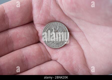 Un homme tenant argent américain quart de dollar pièce, 25 cents, USA Banque D'Images