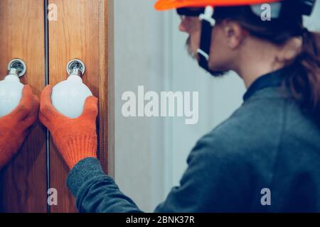 Un électricien remplace la lampe à la maison ou au bureau. Gros plan sur un homme en vêtement de travail réparant un éclairage électrique. Concept dangereux, haute tension, risque, remplacement du câblage, métier du technicien. Banque D'Images