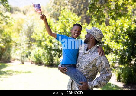 Homme afro-américain portant un uniforme militaire tenant son fils Banque D'Images