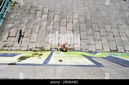 Brighton UK 15 mai 2020 - UN mouette vole par une jeune femme qui prend le soleil sur le front de mer de Brighton pendant une journée ensoleillée sur la côte sud . Cependant, les députés de Brighton espèrent que les foules ne descendent pas sur le front de mer ce week-end, la première après que les gouvernements aient eu un léger assouplissement des restrictions de verrouillage en Angleterre pendant la pandémie du coronavirus COVID-19 . Crédit : Simon Dack / Alamy Live News Banque D'Images