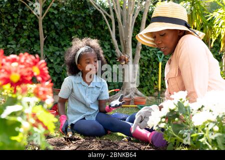 Une fille afro-américaine et sa grand-mère plantent des fleurs dans leur jardin Banque D'Images