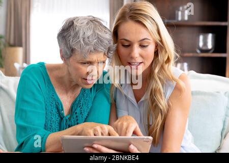 Femme de race blanche et sa fille adulte utilisant un comprimé à la maison Banque D'Images
