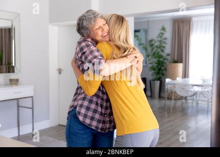 Femme de race blanche et sa fille adulte qui embrasse et sourient à la maison Banque D'Images
