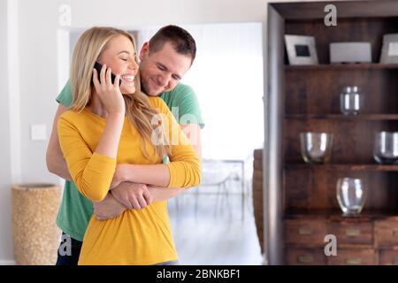 Couple caucasien souriant et embrassant à la maison Banque D'Images