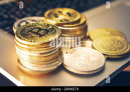 Gros plan de la devise de crypto Bitcoin représentée par des pièces d'or empilées proprement dans les piles sur la table à côté du clavier d'ordinateur. Banque D'Images