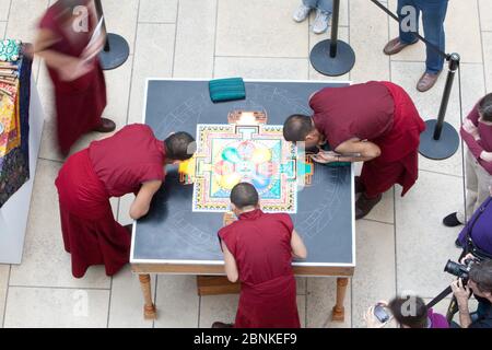 Austin, Texas États-Unis, 11 janvier 2013: Des moines bouddhistes tibétains du monastère de Drepung Loseling construisent un mandala de sable à grande échelle complexe et à motifs en utilisant des millions de grains de sable coloré à l'Université du Texas au musée d'art d'Austin Blanton Un mandala de sable est ritualistiquement détruit une fois qu'il a été achevé et ses cérémonies d'accompagnement et de visualisation sont terminées pour symboliser la croyance doctrinale bouddhiste dans la nature transitoire de la vie matérielle. Banque D'Images