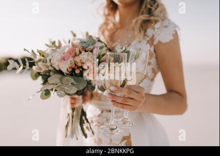 Gros plan du bouquet de roses de pêche, des œillets, de l'eucalyptus d'une mariée. La mariée dans une robe blanche tient un bouquet dans sa main Banque D'Images