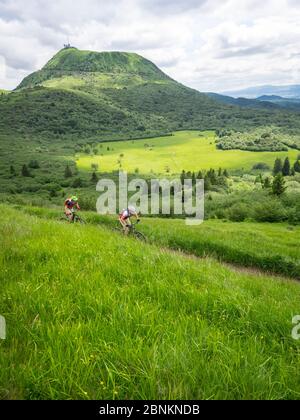 Piste de vélo de montagne unique au Puy Pariou (1209m). En arrière-plan, le Puy de Dôme (1465m), un pic volcanique du massif Central en France. Il fait partie de la chaîne des Puys, la chaîne de montagnes des Puys, avec 80 volcans. Banque D'Images