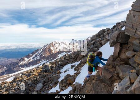 Une femme grimpante se brouille au-dessus des rochers sur le mont Ruapehu, dans le parc national de Tongariro, en Nouvelle-Zélande Banque D'Images