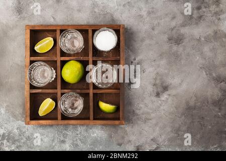 Tequila projectiles, limes et sel sur planche en bois sur fond gris. Vue de dessus, espace de copie Banque D'Images