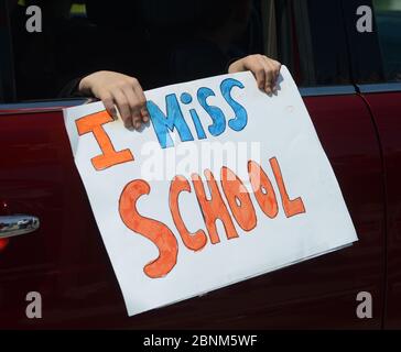 Uper Macungie, États-Unis. 14 mai 2020. Un enfant porte un panneau « I Miss School » ainsi qu'un groupe de partisans de Trump se rassemblent de l'autre côté de la rue depuis un site que le président a visité le jeudi 14 mai 2020 dans l'uper Macungie. La parade a été organisée par la communauté locale avec l'aide d'un ancien enseignant du primaire. Crédit : William Thomas Cain/Alay Live News Banque D'Images