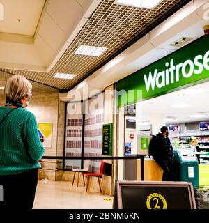 Femme en ligne pour entrer au supermarché Waitrose en observant la distanciation sociale pendant l'épidémie de coronavirus Banque D'Images