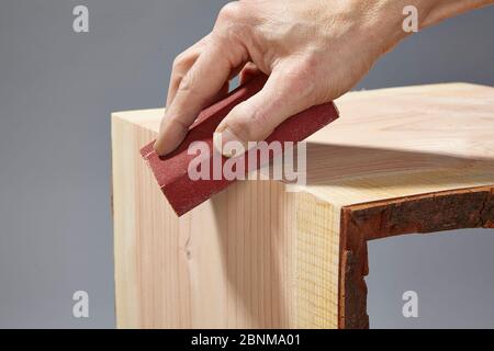 Construction d'une étagère en bois, production par soi-même, étape par étape, étape 9 ponçage du bord extérieur après le durcissement de la colle à l'aide d'un bloc de ponçage Banque D'Images