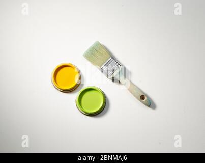 Utilisateur et délavé brosse en bois avec deux couvercles de boîtes de peinture, jaune et vert sur fond blanc Banque D'Images