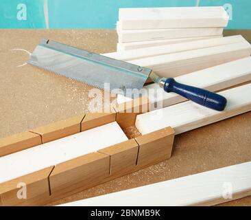 Bricolage mur conception 02, étape par étape faire-il-vous production, diverses zones de couleur turquoise séparées par des bandes de bois blanc, étape 06: Couper les bandes de bois à la longueur dans un tiroir de scie avec une scie Banque D'Images