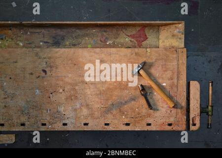 ancien établi en bois, photographié graphiquement d'en haut, plancher d'atelier gris foncé, avec peu d'outils, rangé, variante 2 de 5 Banque D'Images