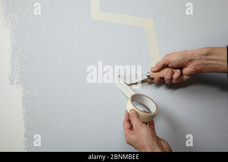 Bricolage mur conception 03, étape par étape faire-il-soi-même production, diverses zones colorées avec peinture murale et plâtre à rouleau, gris et jaune, pointe pour l'étape 2: Déchirez le ruban sur le bord d'une spatule de peintre pour obtenir une finition droite Banque D'Images