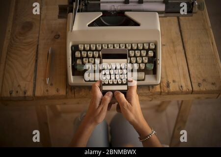 Concept, écriture et travail avec une technologie ancienne et moderne, nouvelle, femme prend une photo d'une machine à écrire avec son téléphone cellulaire Banque D'Images