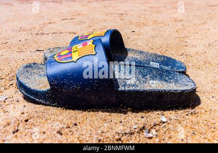 Pantoufles bleues sur le sable de la plage de Candolim située dans le nord de Goa, Goa, Inde avec un club de football appelé logo Barcelone. Plage de sable à Goa. Banque D'Images