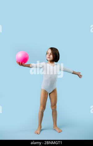 Petite fille dans un léopard blanc avec ballon de gymnastique sur bleu Banque D'Images