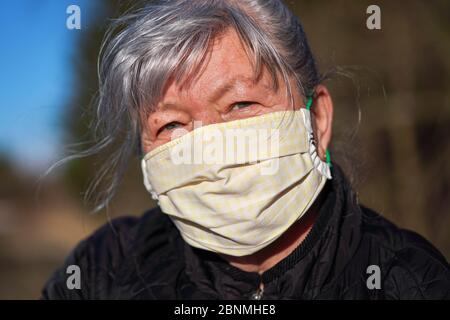 Femme âgée âgée avec cheveux gris portant un tissu fait maison visage bouche nez virus masque extérieur. Peut être utilisé pendant la préve de l'éclosion du coronavirus Covid-19 Banque D'Images