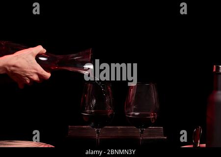 Verser deux verres à vin sur fond noir, une bouteille de vin en verre et des ustensiles de vin Banque D'Images