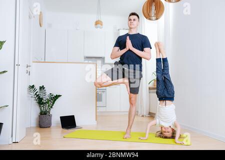 Père et fils faisant du yoga à la maison sur un tapis. Support de tête et un support de jambe Banque D'Images