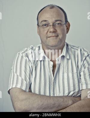 Un homme âgé avec des lunettes et une tête chauve sourit à la caméra Banque D'Images