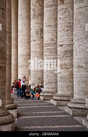 Groupe scolaire prenant refuge du soleil dans les colonnes de la place St Peters à Rome Banque D'Images