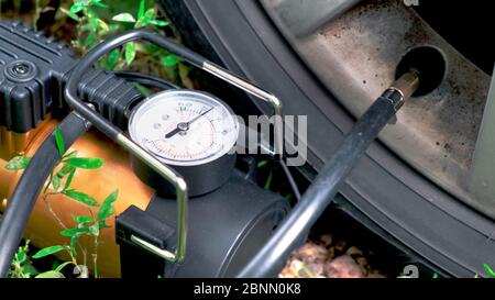 Câble de compresseur de voiture pour pomper dans un pneu de voiture sur un disque. Processus de pompage. Banque D'Images