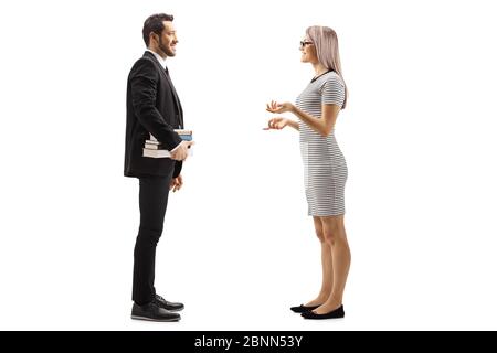 Photo pleine longueur d'un homme en costume noir tenant des livres et parlant avec une jeune femme blonde isolée sur fond blanc Banque D'Images