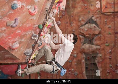 Jeune homme pratiquant au mur d'escalade intérieur au Royaume-Uni Banque D'Images