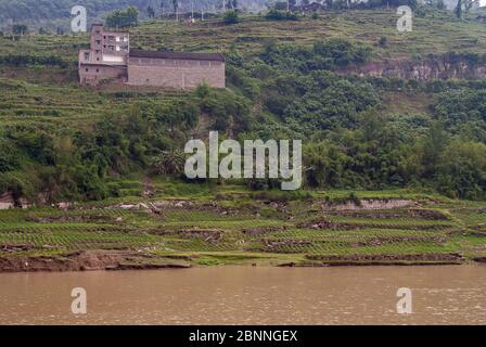 Fengdu, Chongqing, Chine - 8 mai 2010 : fleuve Yangtze. Paysage avec maison de ferme en pierre brune et jardin de légumes dans les terrasses au bord de la côte sur le plat Banque D'Images