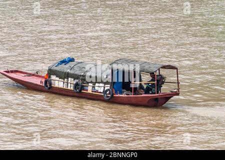 Fengdu, Chongqing, Chine - 8 mai 2010 : fleuve Yangtze. Gros plan de petite boucle rouge avec cabine vert foncé et homme sur moteur, tout sur l'eau brune. Banque D'Images