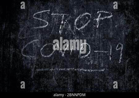 Stop COVID 19 écrit sur un mur de texture rugueuse avec de la craie rose, plan horizontal. Banque D'Images