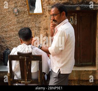 Un barbier qui coupe les cheveux dans une saloon. Banque D'Images