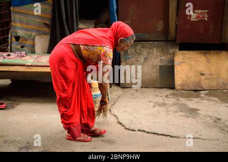 Une femme balayant le sol avec un balai. Banque D'Images