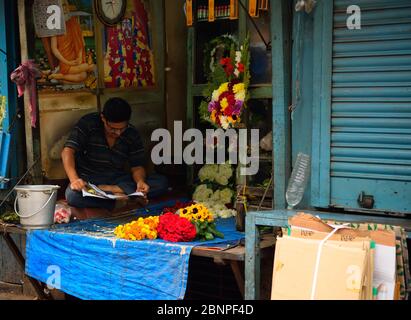 Un homme lisant un journal dans sa boutique Banque D'Images