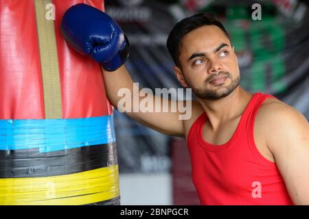 Jeune homme indien barbu comme boxeur portant des gants à la salle de gym Banque D'Images