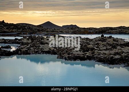 L'eau thermale de la centrale géothermique de Svartsengi, colorée en bleu par des diatomées, dans le champ de lave couvert de mousse Illahraun près de Grindavik sur la péninsule de Reykjanes. En arrière-plan le volcan Thordarfell. En soirée lumière. Banque D'Images