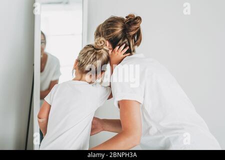 Les jeunes filles et les jeunes mères en T-shirts blancs regardent dans le miroir, les gens de derrière Banque D'Images