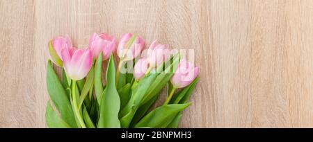 Tulipes roses rouges sur une table en bois clair Banque D'Images