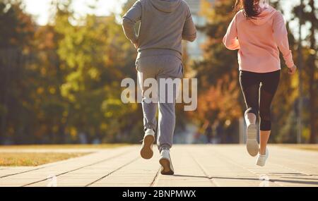 Un homme et une femme dans des vêtements de sport sont en train de courir le matin dans la rue de la ville. Les coureurs sont en train de courir en ville..Jogging. Santé. Mode de vie sain. Banque D'Images