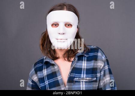 Jeune homme taille basse avec cheveux longs portant un masque Banque D'Images
