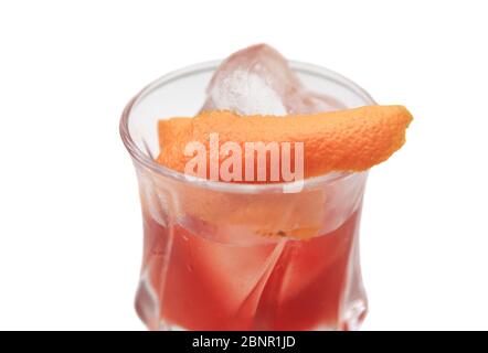 Cocktail brun rougeâtre dans un verre rocailleux sur un fond blanc isolé. Le cocktail est garni d'une touche orange et de glace coupée à la main. Banque D'Images