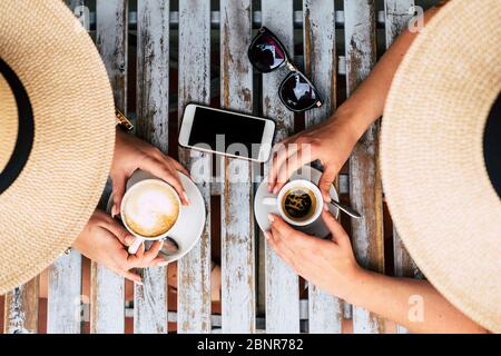 Au-dessus de la vue vetical de couple de gens de race blanche, les femmes se sont associées et ont pris le café italien et le cappuccino au bar - concept de l'amitié et de style de vie alternatif lgbt - en bois, table à la mode en plein air Banque D'Images